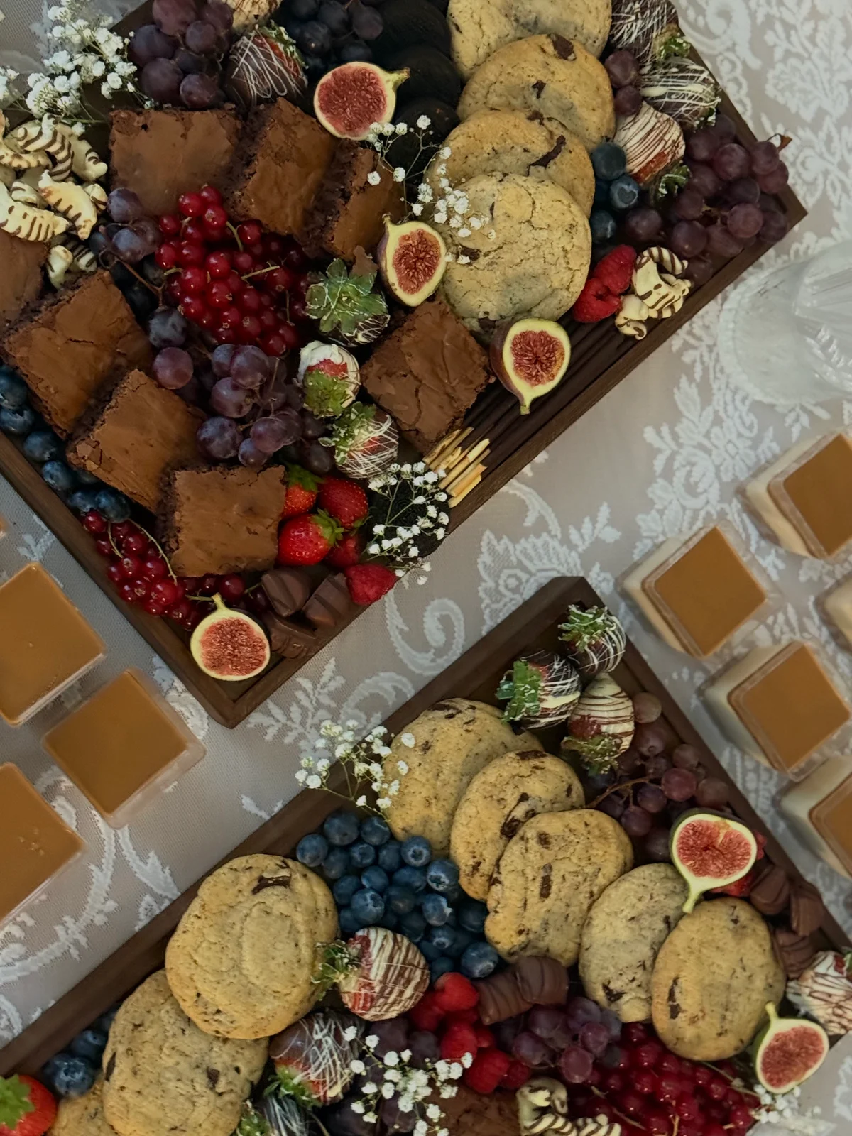 Dessertplatten von oben: Gebäck, Beeren, Feigen und schokolierte Früchte, mit kleinen weißen Blüten arrangiert